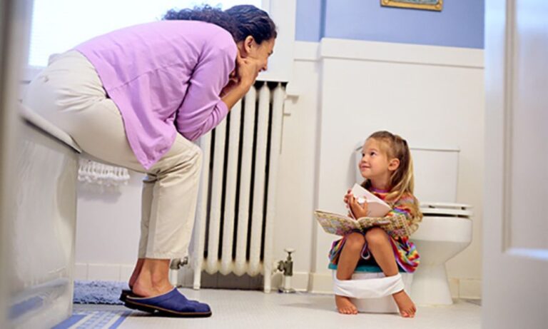A parent encouraging their toddler during potty training at home, showing calm support and positive bathroom routine.