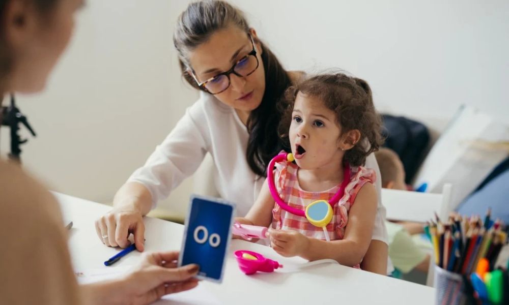 Pediatrician talking to a toddler during a speech delay evaluation, checking hearing and communication skills.