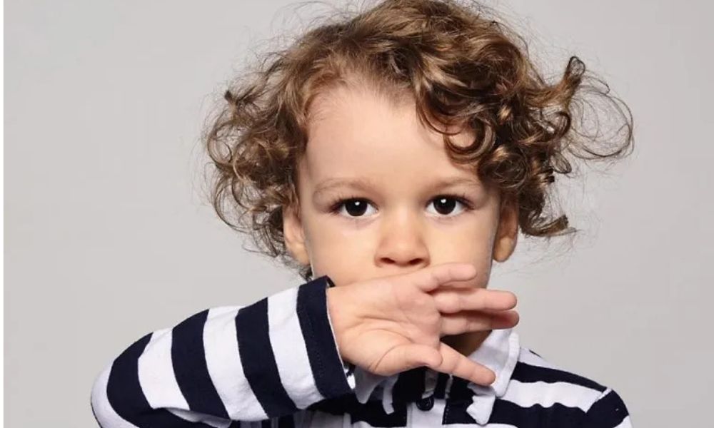 Toddler covering mouth, representing early signs and red flags of speech delay in toddlers.