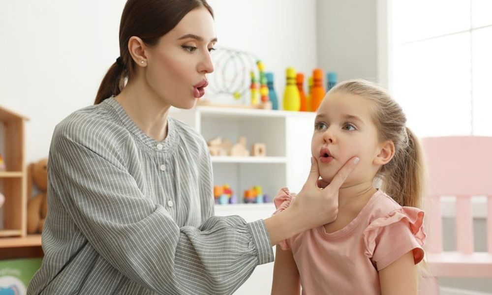 Speech therapist guiding a young girl to practice mouth movements during speech delay therapy.